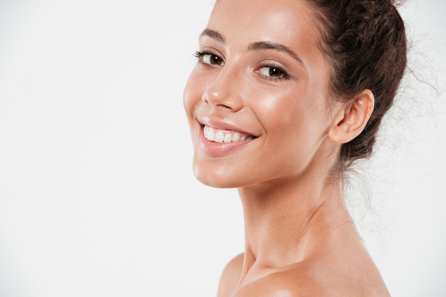 Retrato de mujer sonriente con la piel del rostro luminosa sobre fondo blanco